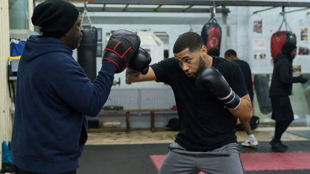 Adult boxer working mid-range hooks and uppercuts on focus mitts with a coach