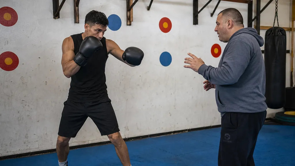 Coach calling numbers during a controlled boxing reaction drill on pads