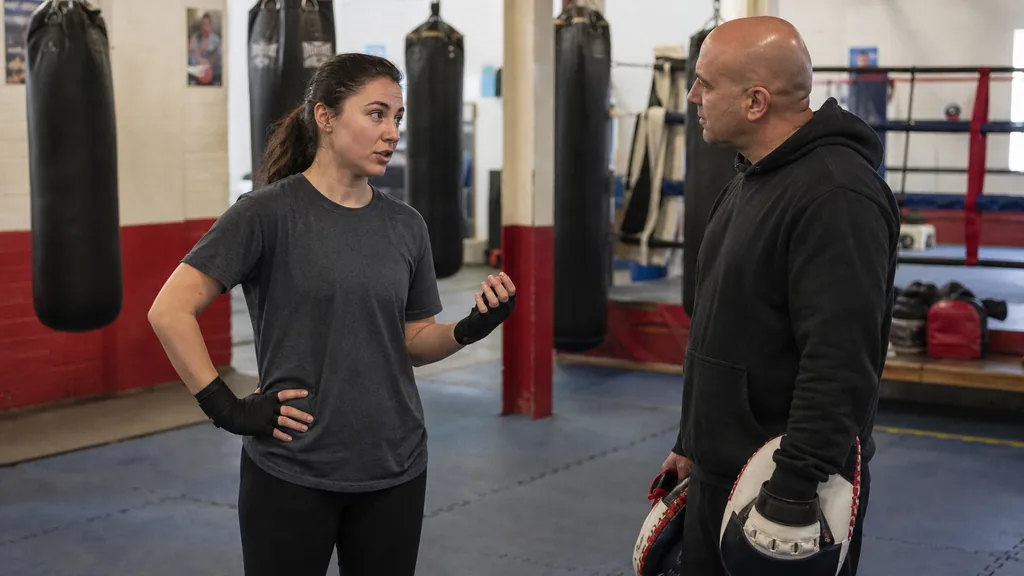 Adult boxer speaking privately with a coach before choosing a lighter pad-work session