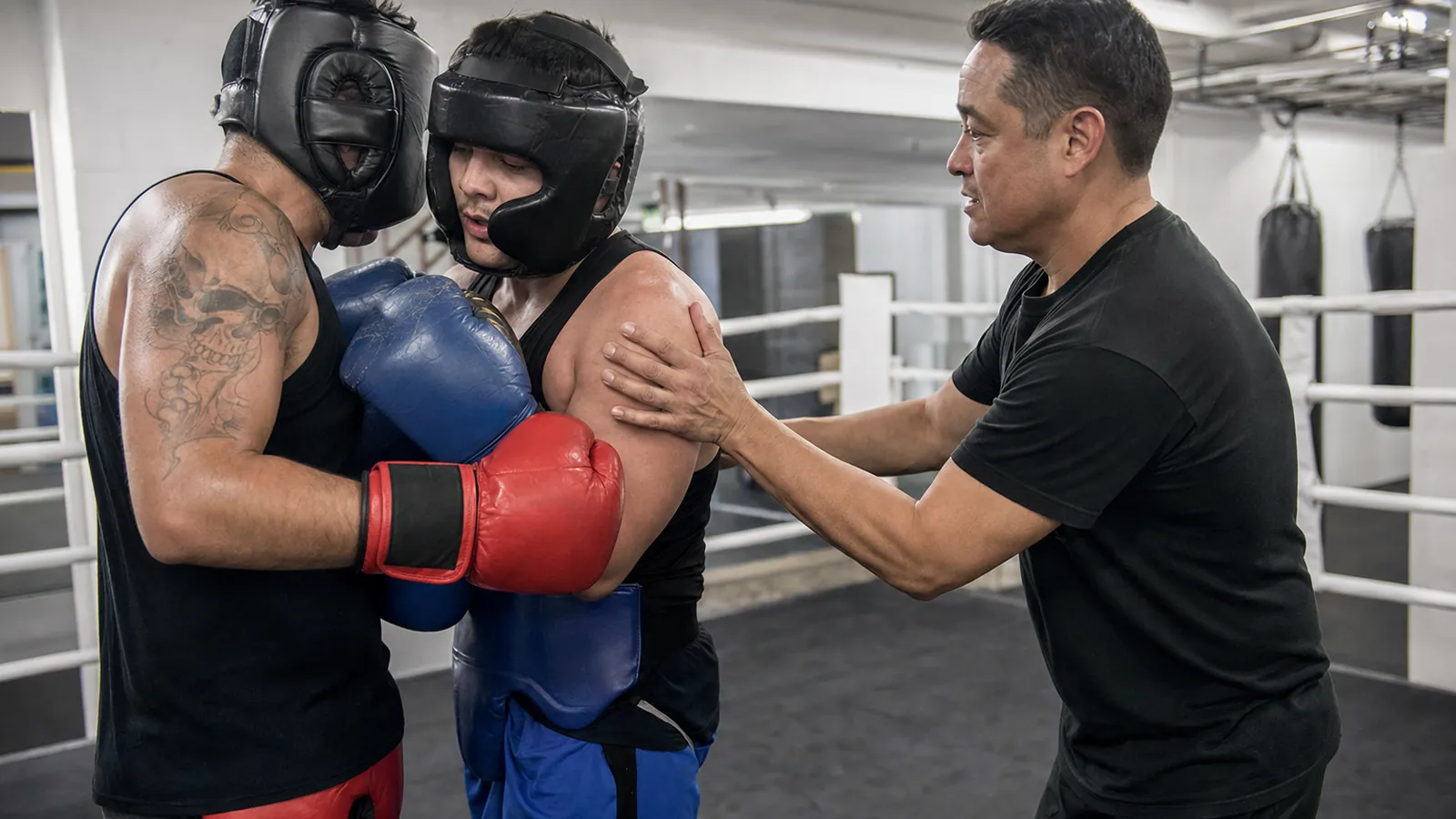 Coach-referee separating two adult boxers during controlled close-range training