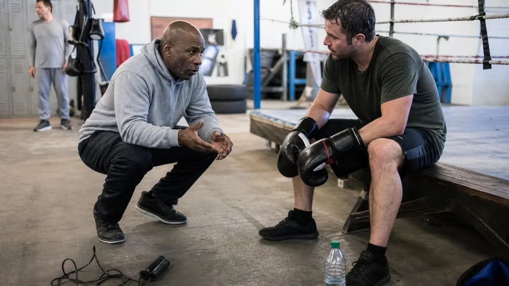 Boxing coach explaining recovery pacing during a beginner fitness session