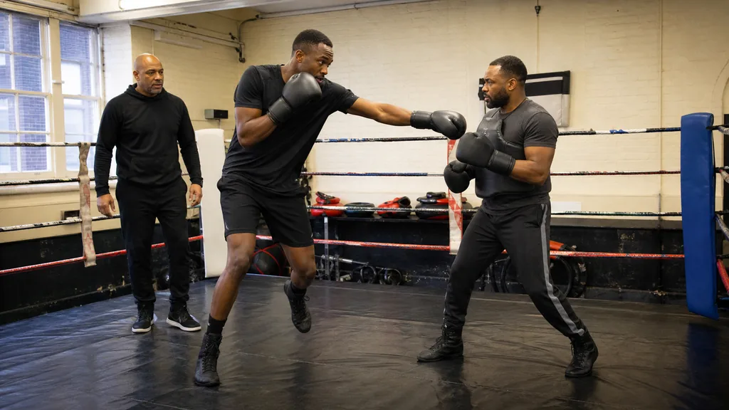 Adult boxer working a long jab into focus mitts before a controlled step-back reset