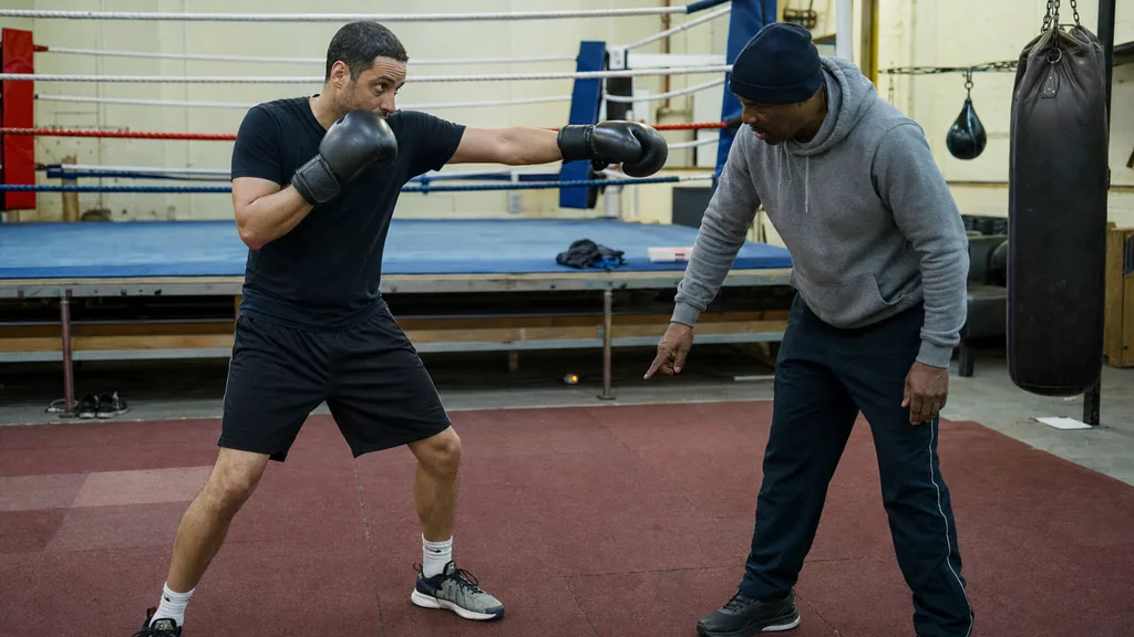 Adult boxer stepping forward behind a jab while a coach checks foot position