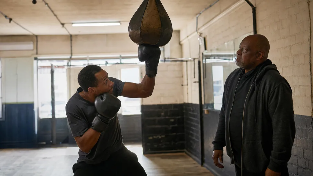 Adult boxer practising a compact uppercut on a heavy bag while a coach watches body position