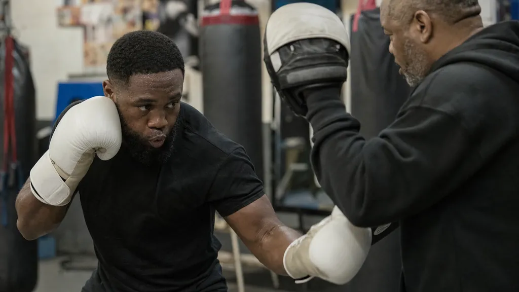 Adult boxer practising a compact uppercut on pads while keeping the rear hand high