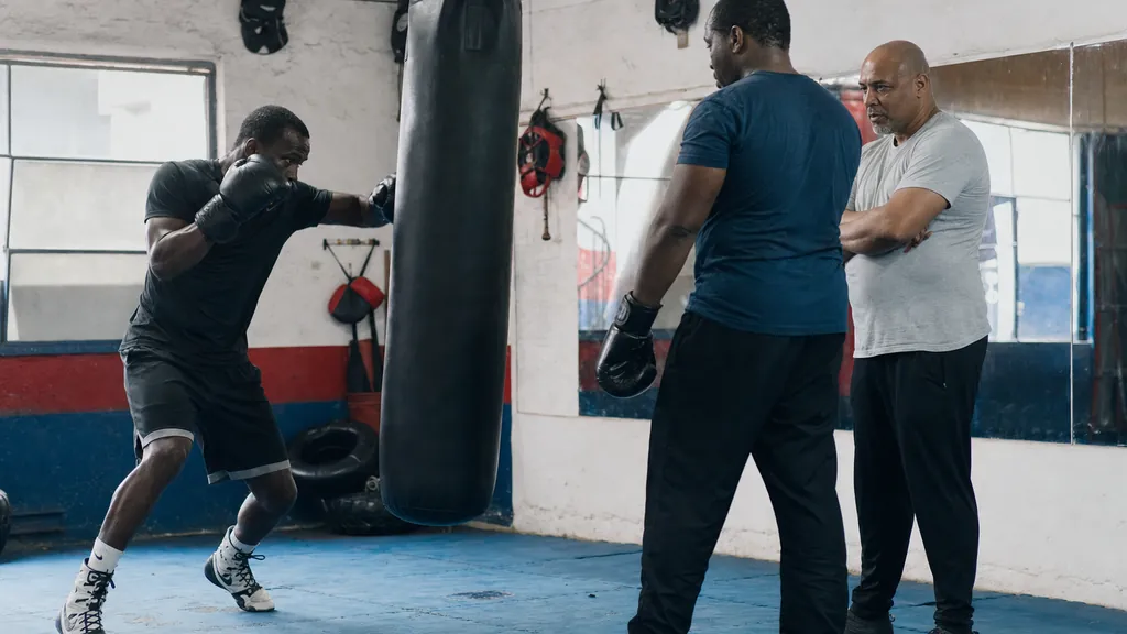 Adult boxer throwing a compact lead hook on a heavy bag with the rear hand held tight to the cheek