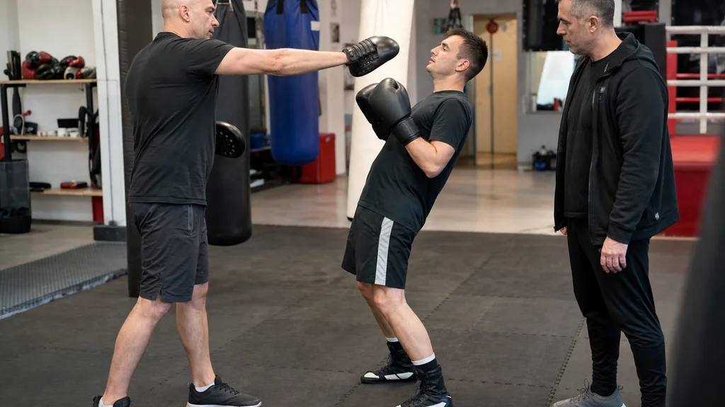 Adult boxer practising a small layback on focus mitts in a community boxing gym