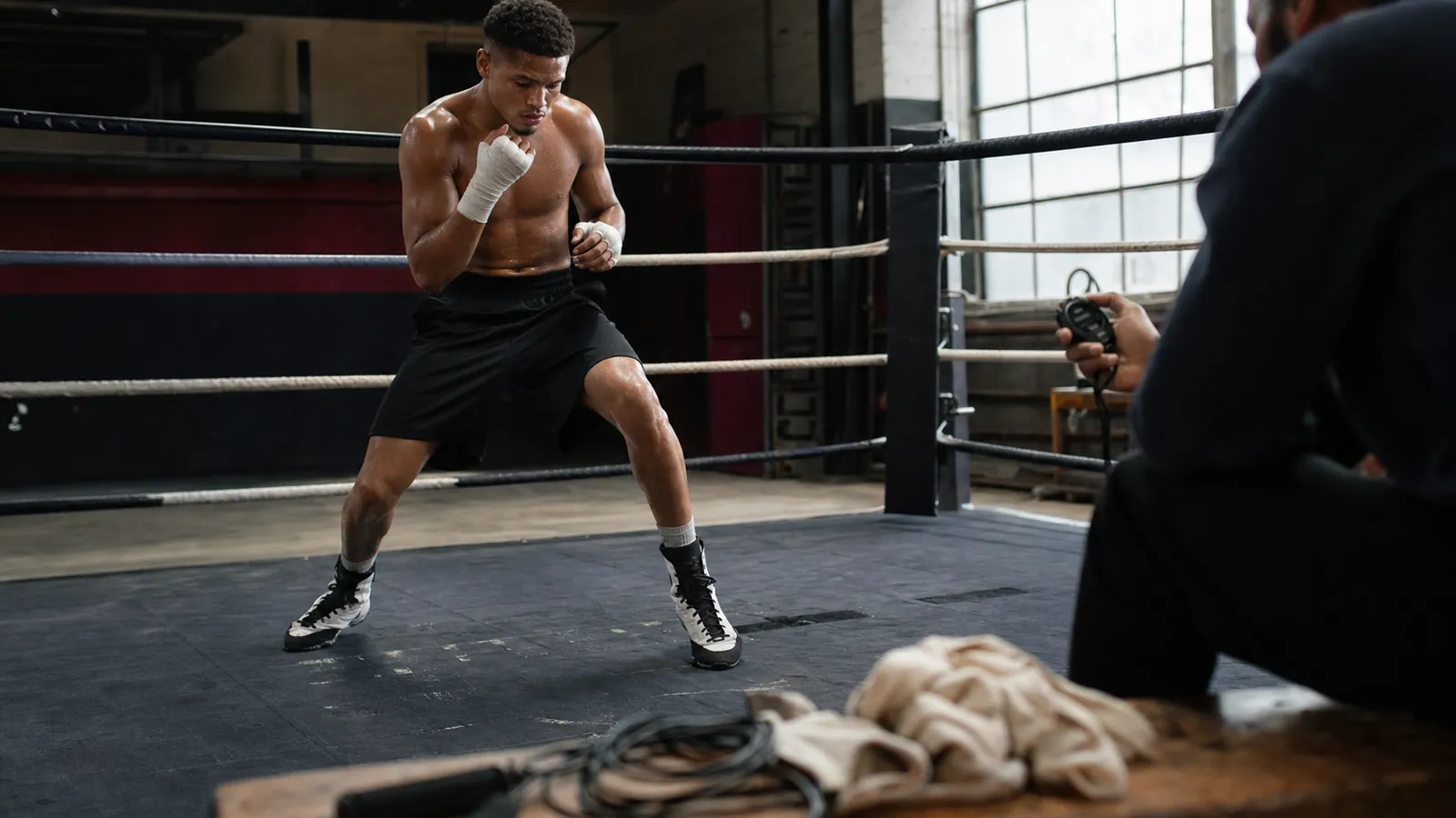 Coach reviewing ring tactics with a boxer before a serious session