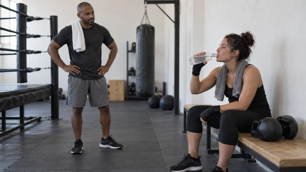 Adult boxer pauses for a small sip of water while a coach checks in after a safe training round