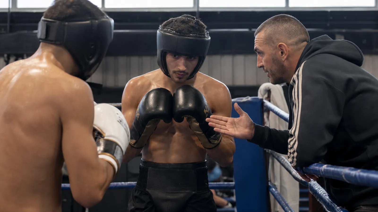 Two boxers sparring under close coach supervision in a serious training gym