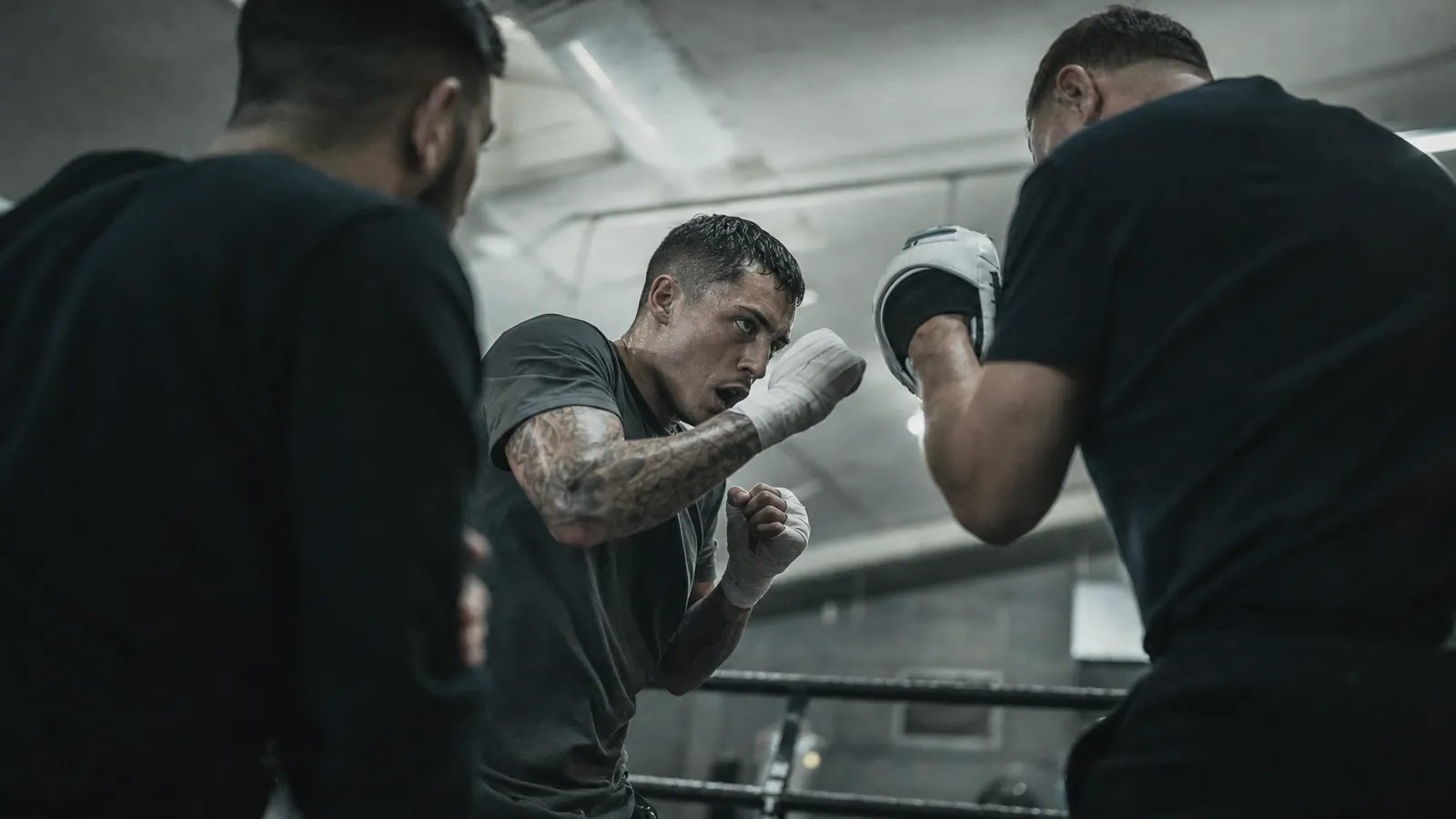 A coach watching a boxer reset between hard technical rounds