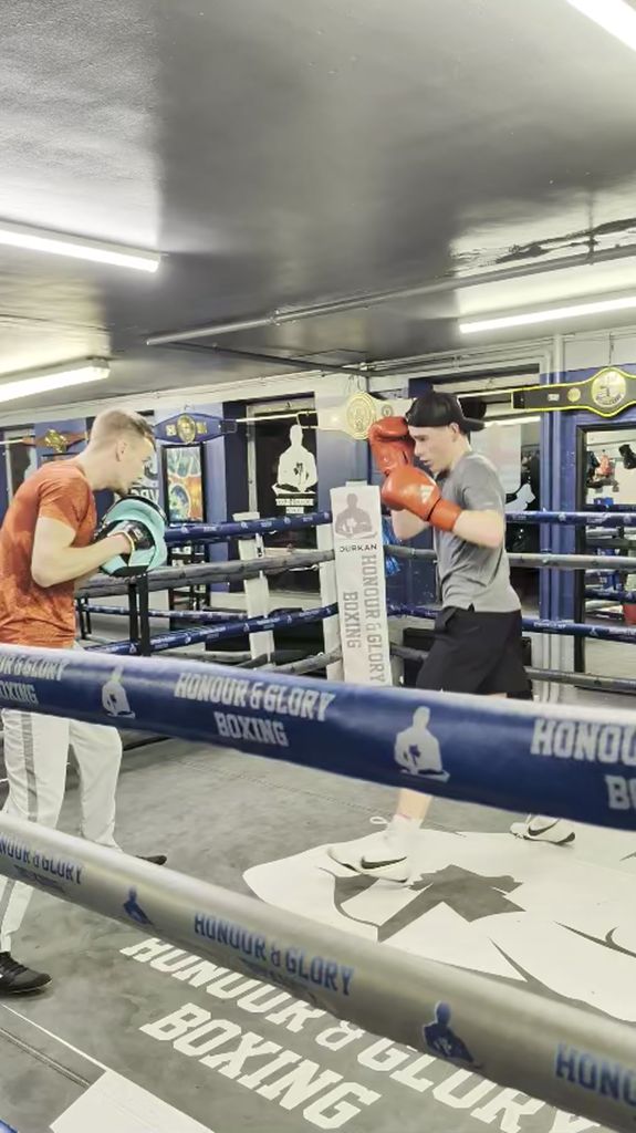 Coach working with young junior boxer on pad technique