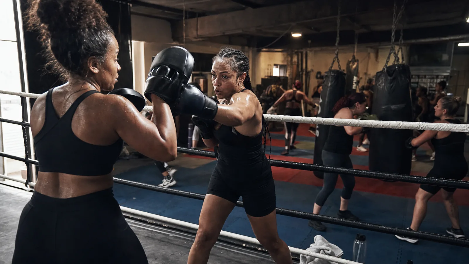 Women training boxing padwork together near Mottingham
