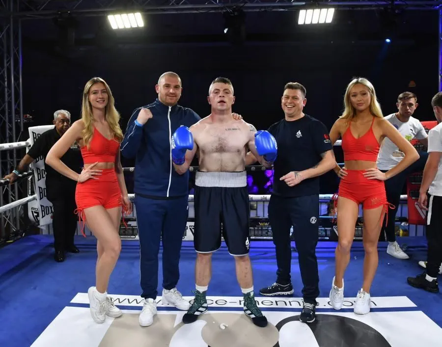A professional boxer standing in the ring with members of his coaching team after a bout